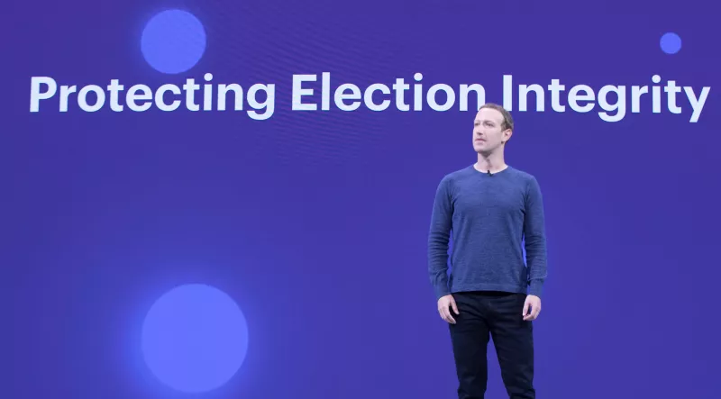 Facebook CEO, Mark Zuckerberg, standing in front of a board that says 