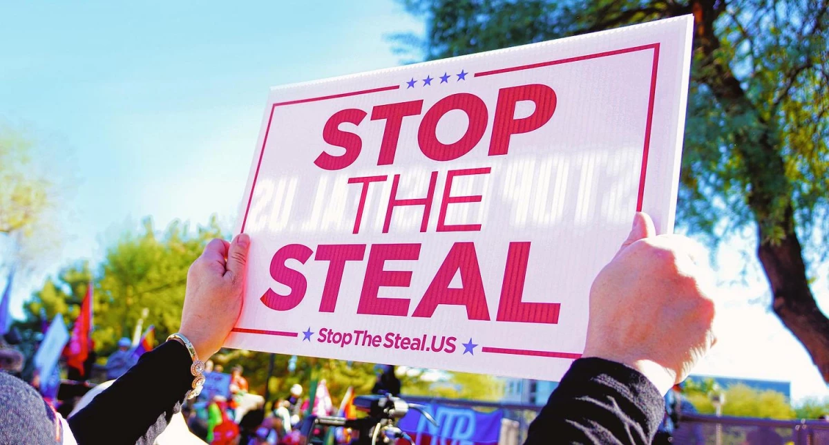 A person holds up a sign reading 