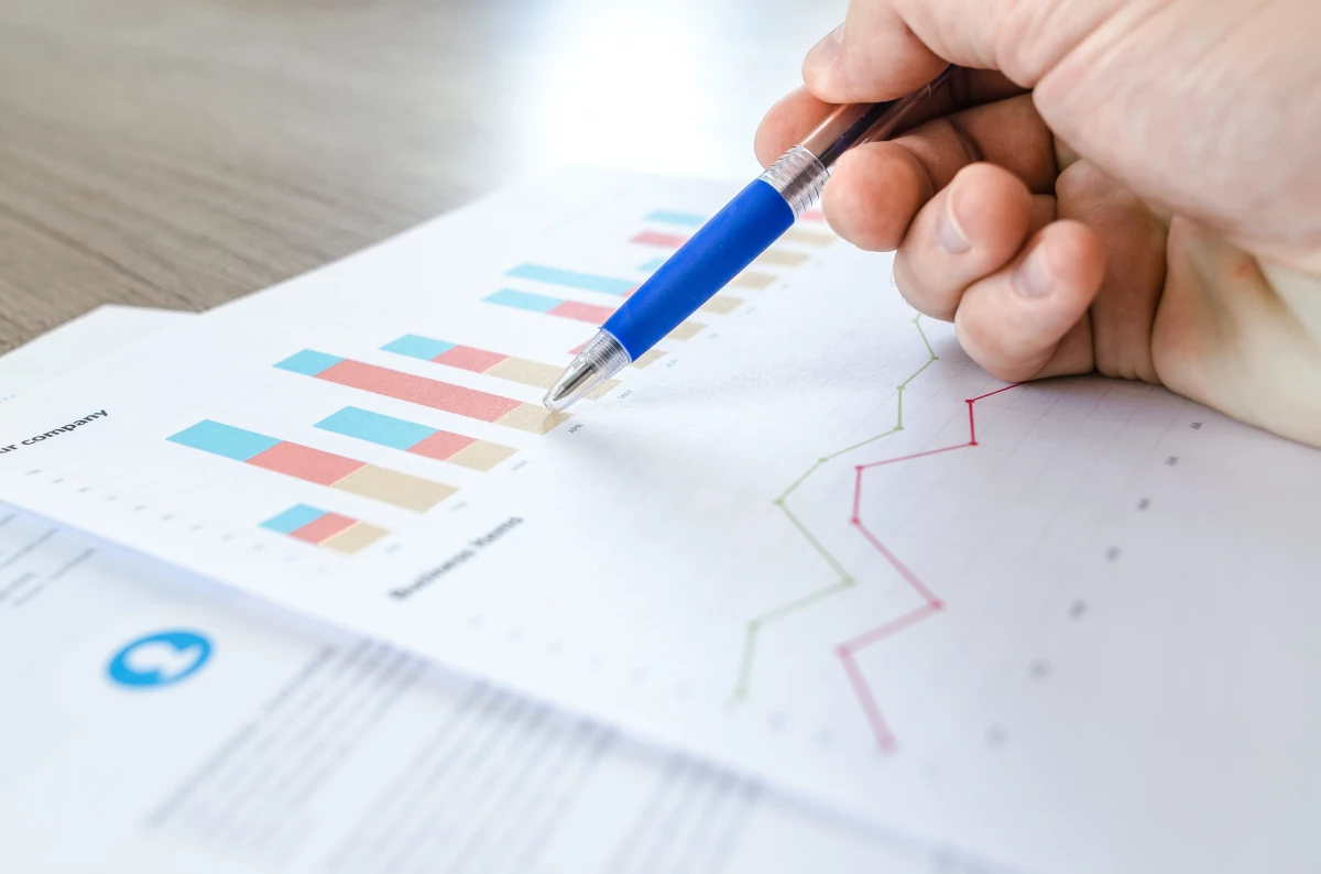 A close up photo of someone using a pen to mark up a piece of paper with data on it.