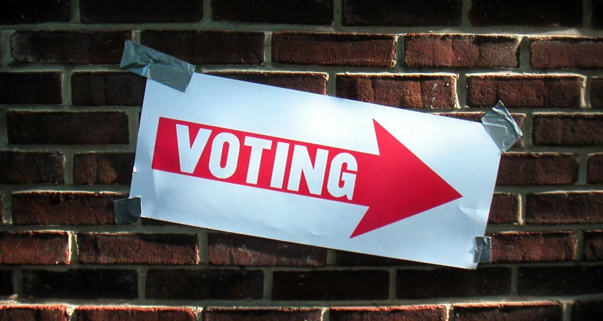 A vote sign taped to a brick wall.